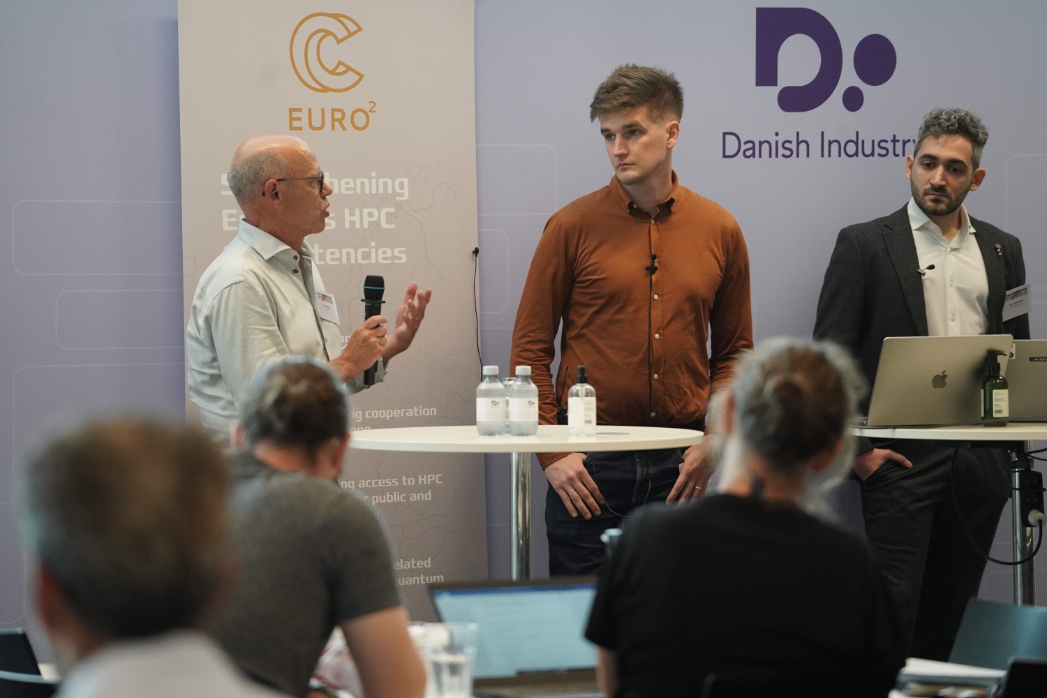 Three people standing during a panel discussion.